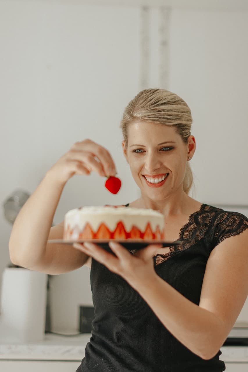 Valentine Lambert posant une fraise sur un fraisier de saison